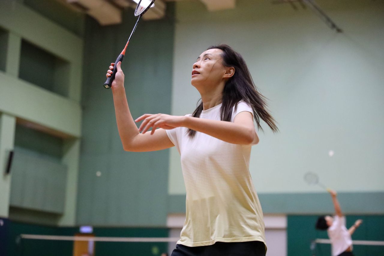 A woman in sportswear concentrating on her badminton game in an indoor court.