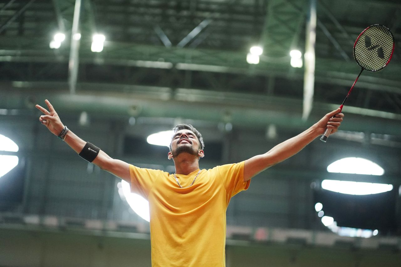 A young boy playing badminton in an indoor gym, focusing on the shuttlecock.