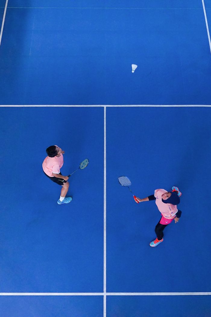 Grayscale image of badminton racket and shuttlecocks on a court surface.