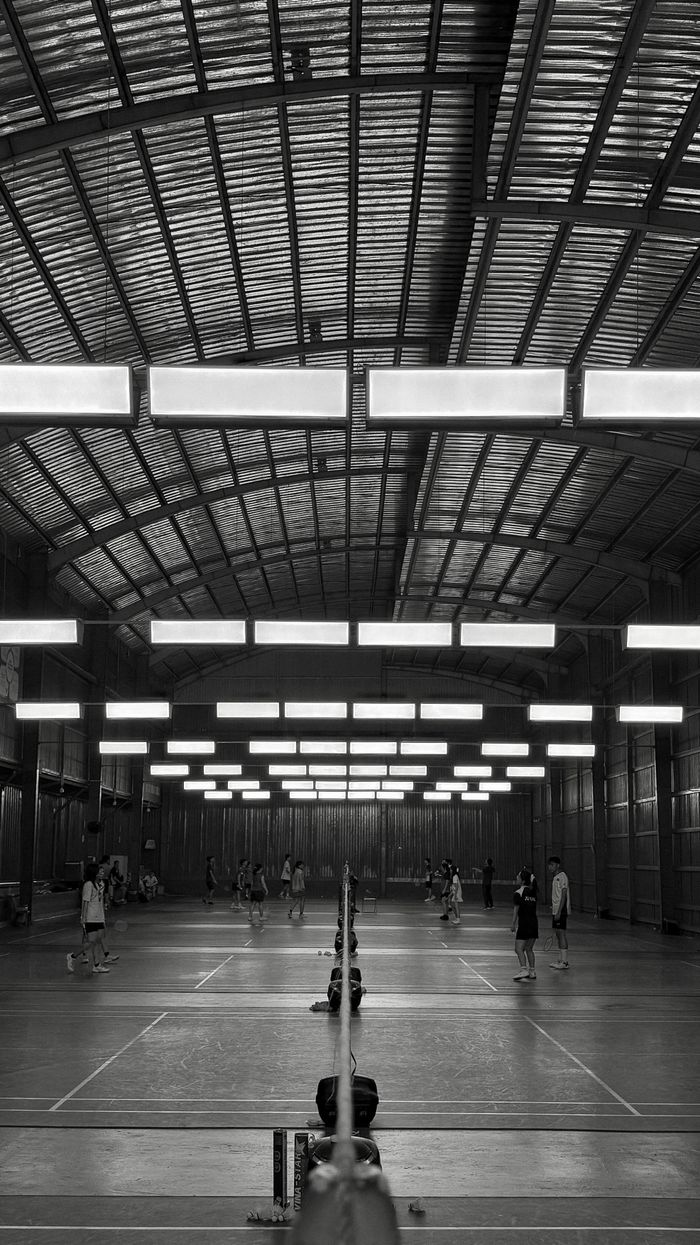 Monochrome view of a busy indoor badminton court in Vietnam.