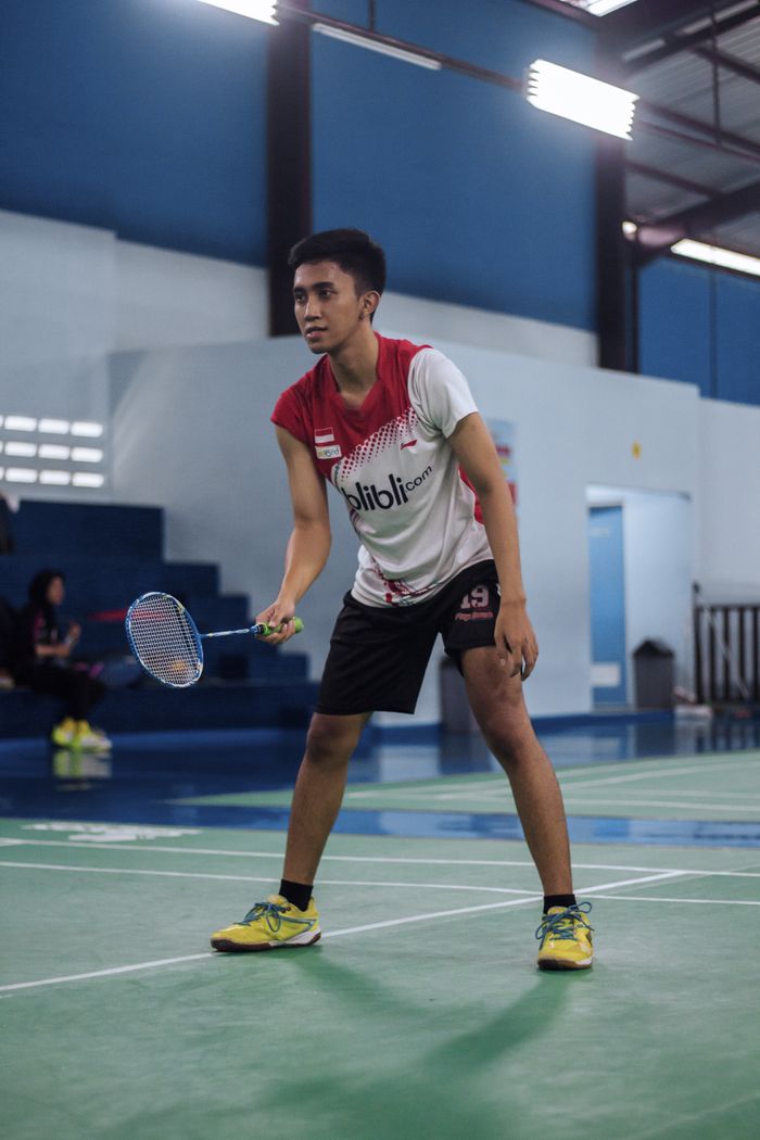 Asian man engaged in a badminton game at an indoor court, showcasing athletic skills.